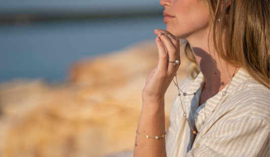 A woman stares out into the distance, looking over at our sustainable pearl farm at Cygnet Bay while wearing her naturally lustrous pearl jewellery pieces.