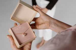 A woman holds her gift that features an Australian South Sea charm alongside an Australian Akoya charm hanging alongside.