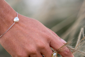 A woman wears her stunning chain bracelet that features an Australian Keshi pearl set on a delicate solid gold chain.