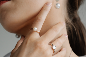 A woman wears her pearl jewellery, each featuring a different type of pearl. From her Mother of Pearl ring set in silver, alongside an Australian Akoya pearl ring set in gold and her Australian South Sea drop earrings set alongside diamonds.