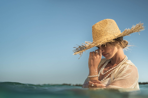 A woman stands in the turquoise waters of our Cygnet Bay Pearl Farm. She wears an array of Pearls of Australia jewellery pieces, including an exquisite pearl strand necklace with a matching pearl strand bracelet, as well as a pearl ring on each hand.
