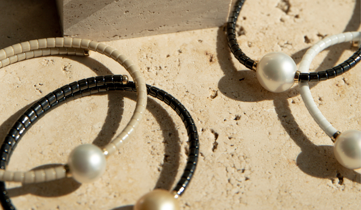 A collection of pearl jewellery pieces part of the Terra Range, featuring ceramic links and set in 18ct yellow gold.