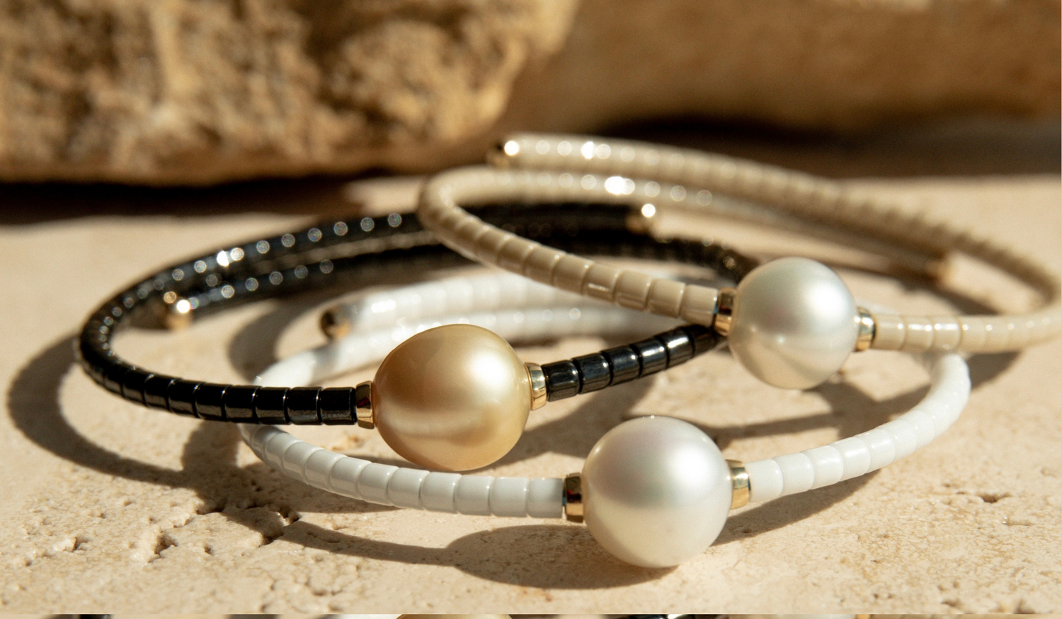A collection of pearl jewellery pieces part of the Terra Range, featuring ceramic links and set in 18ct yellow gold.