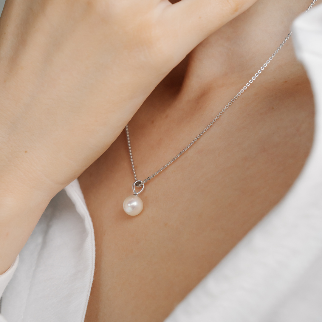 A person wears their stunning Broken Bay grown Akoya pearl pendant on a matching gold chain.
