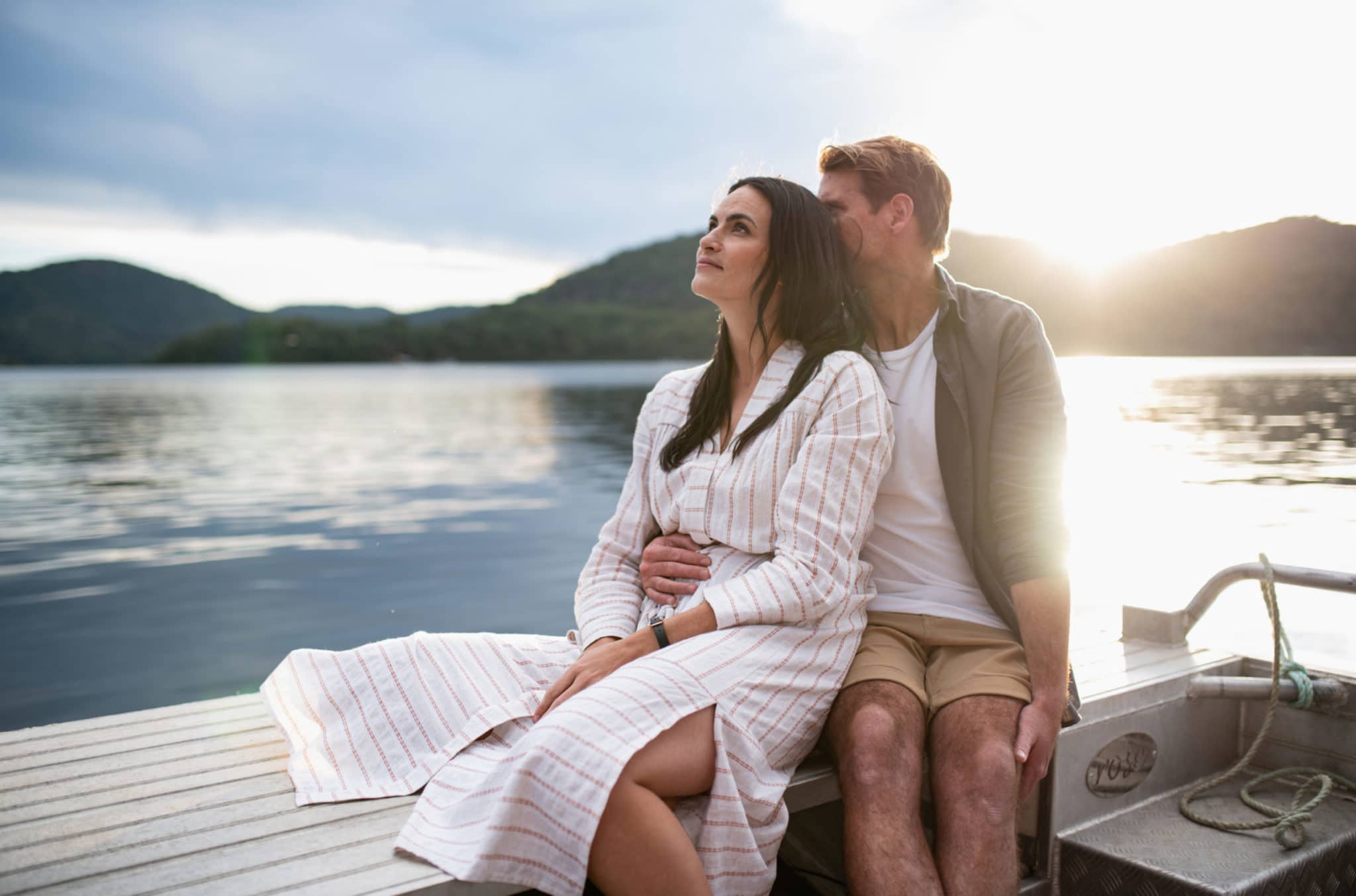 A couple sit on the edge of a farm cruise tour at our Broken Bay Pearl Farm, enjoying their private tour at sunset. Behind them is a beautiful view of Spectacle Island at sunset, with the still azure waters of the Hawkesbury River.
