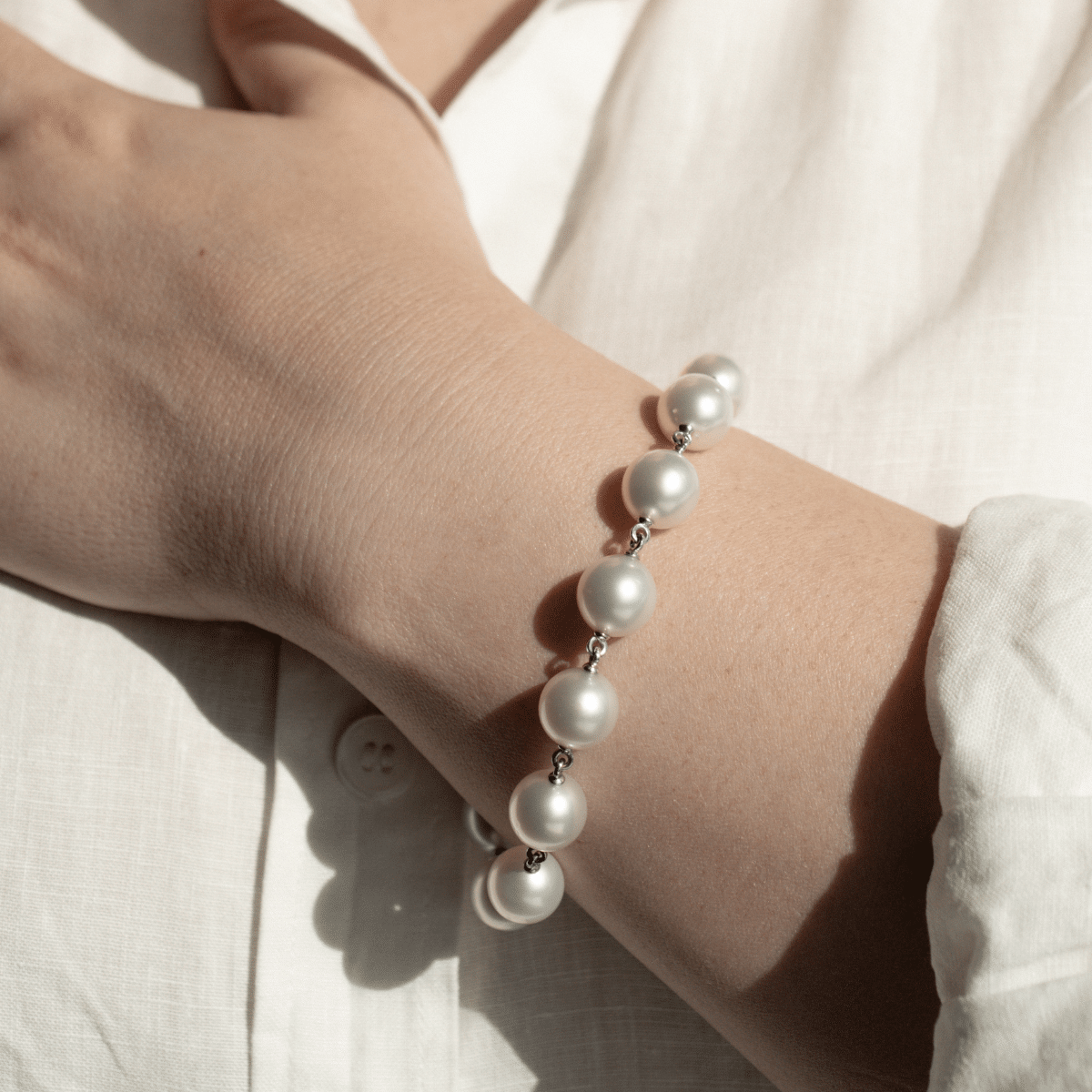 A woman wears her stunning Cocos Pearl Strand Bracelet, with pearls shining with their natural white colour and lustre.