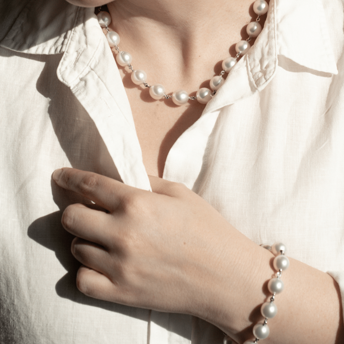 A woman wears her Cocos Pearl Strand Necklace featuring thirteen (13) drop shape Australian South Sea pearls set on a 43cm white gold chain. She wears her matching pearl strand bracelet to complete her set.