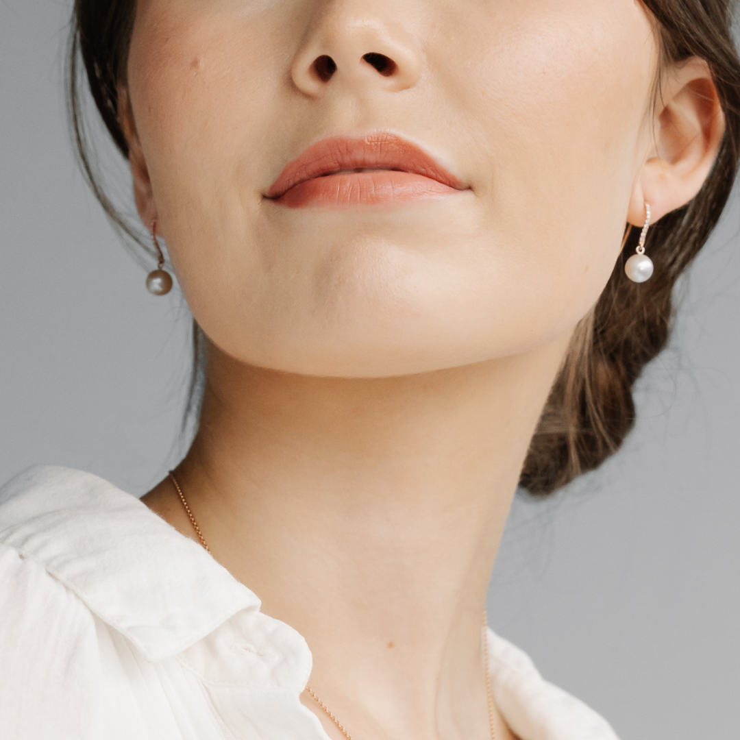 A woman wears her pair of stunning Australian Akoya pearl hook earrings set in gold, with a row of white diamonds.