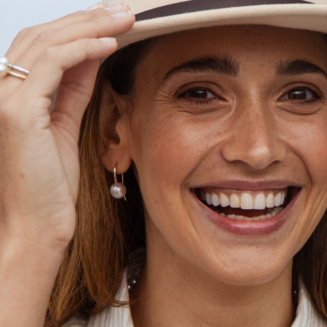A woman wears her pair of beautiful Australian South Sea pearls set on a pair of hook earrings in solid gold.
