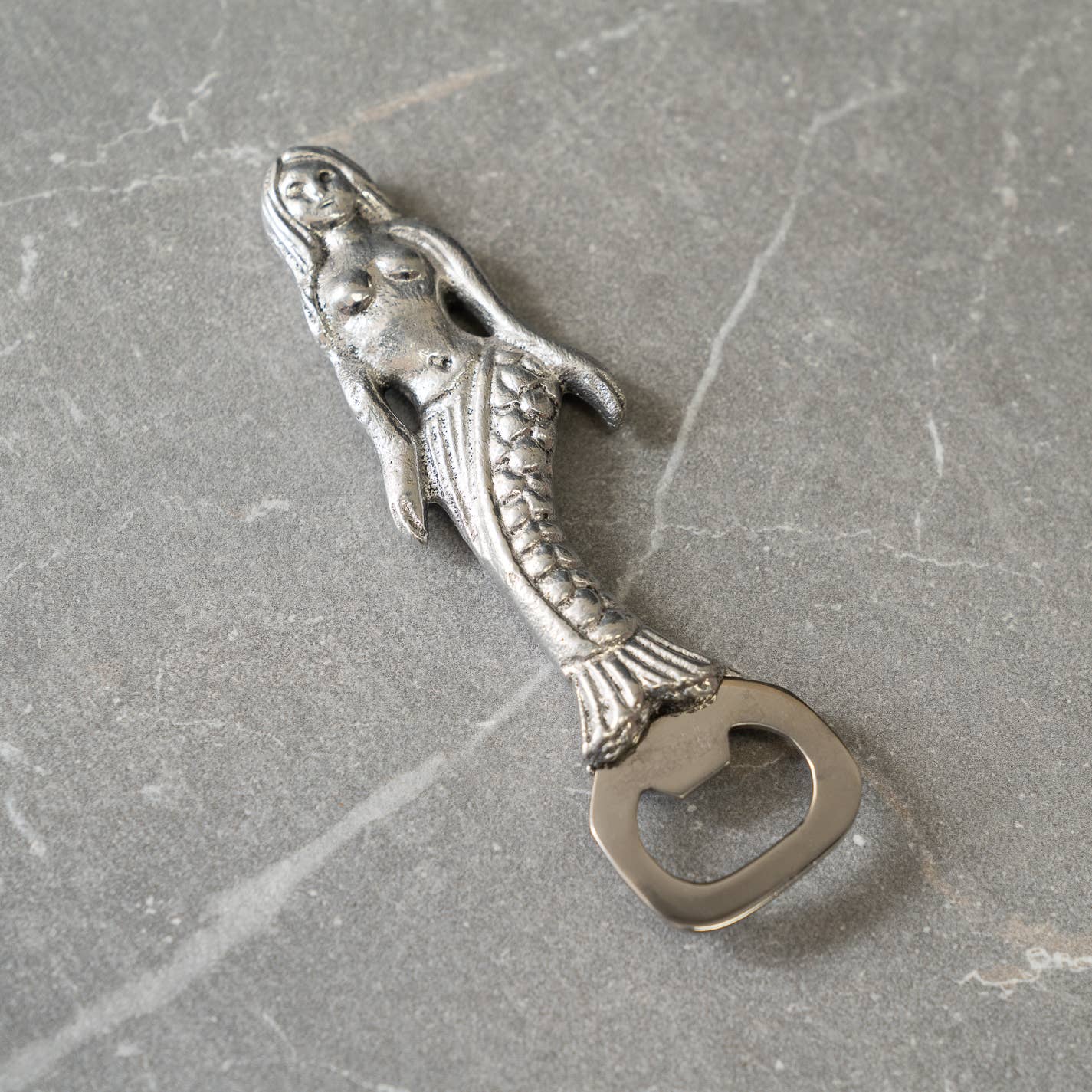 Mermaid-shaped bottle opener on a gray surface