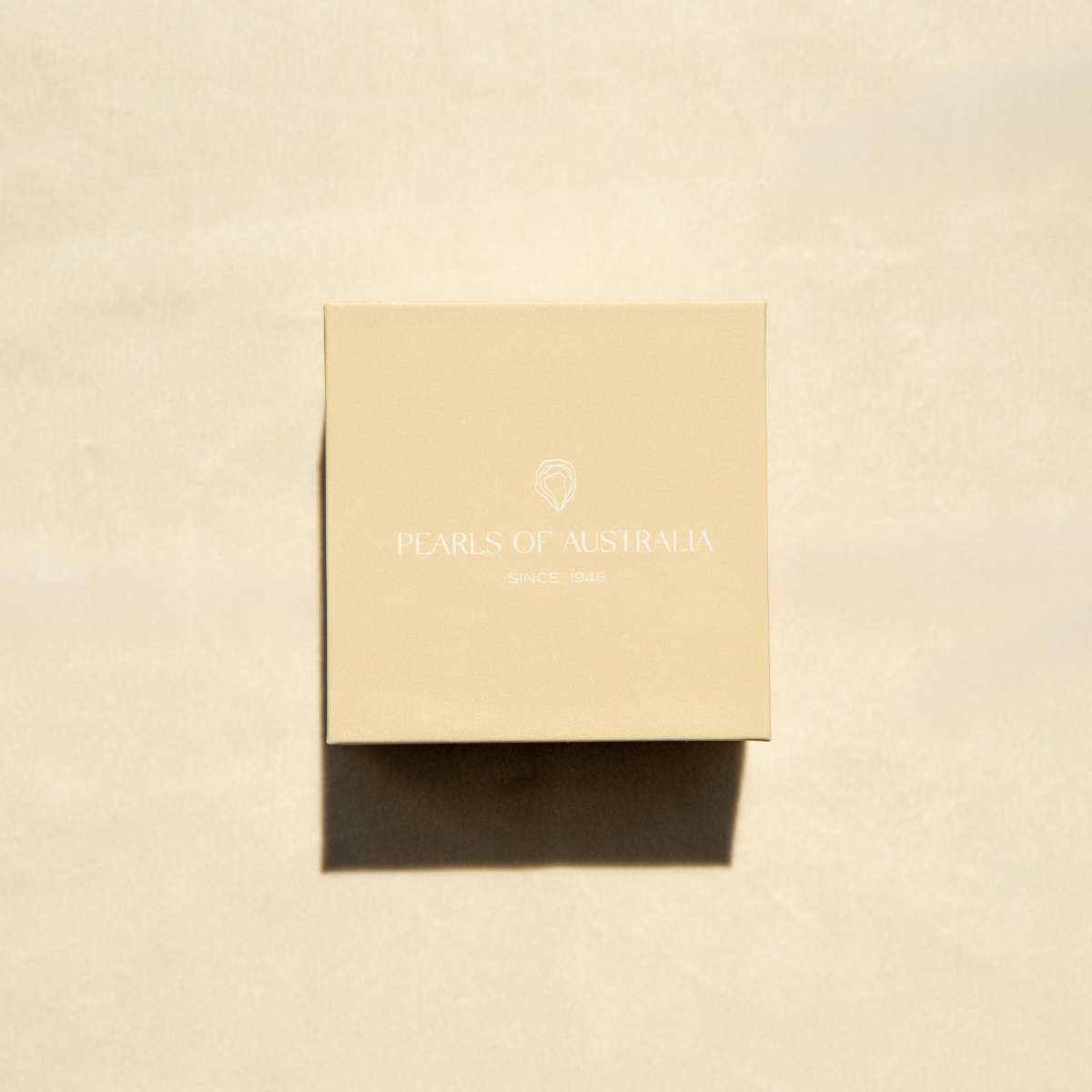 Pearls of Australia gift box on a beige, textured surface.