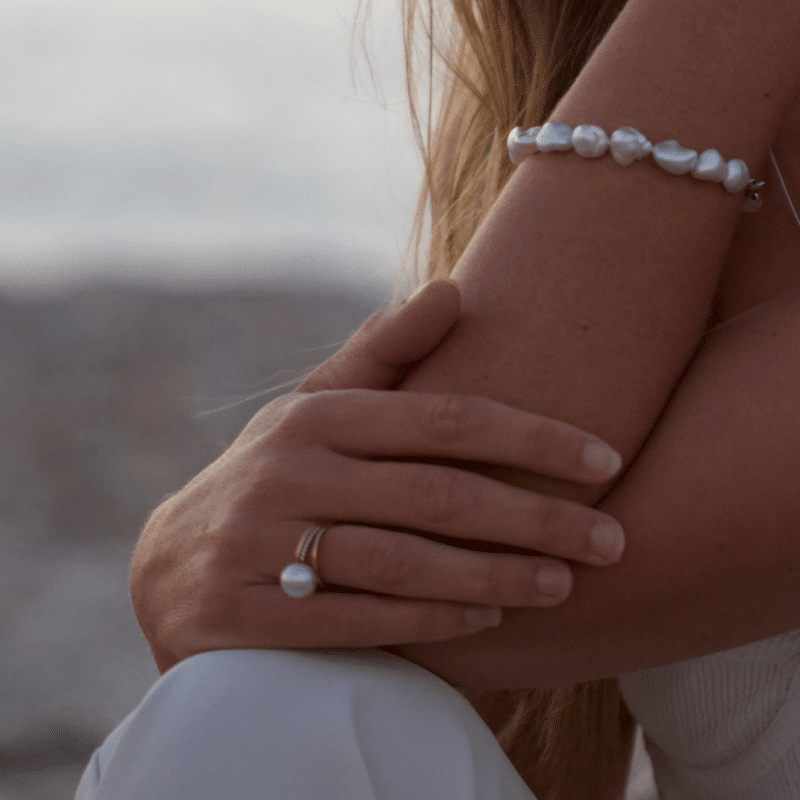 A woman wears her striking pearl ring, featuring an Australian South Sea pearl set alongside a band of white glimmering diamonds.