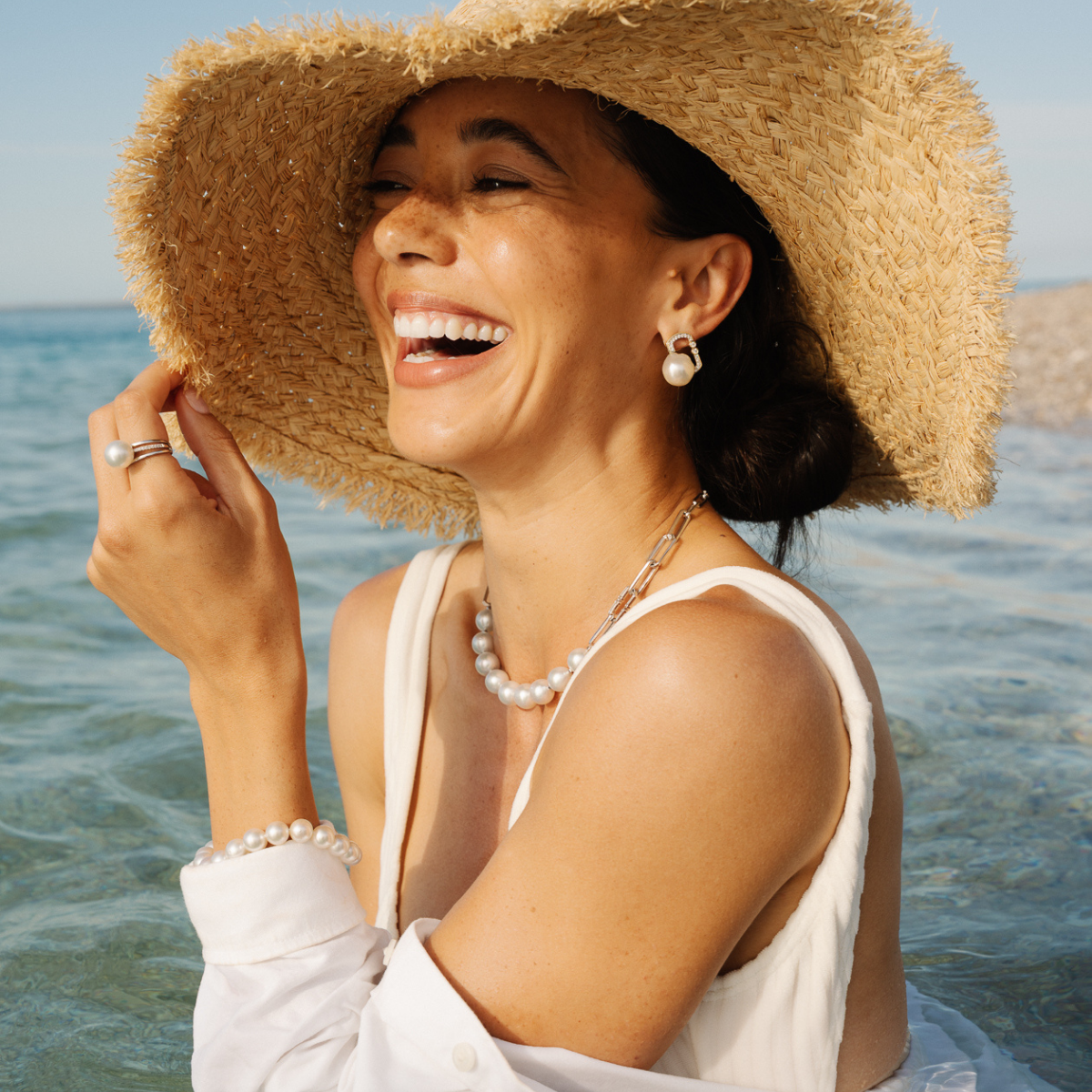 Woman wearing a straw hat and white dress by the water