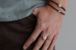 A man wears his Australian pearl jewellery gifts which include a Keshi pearl ring, and a stack of neoprene bracelets.