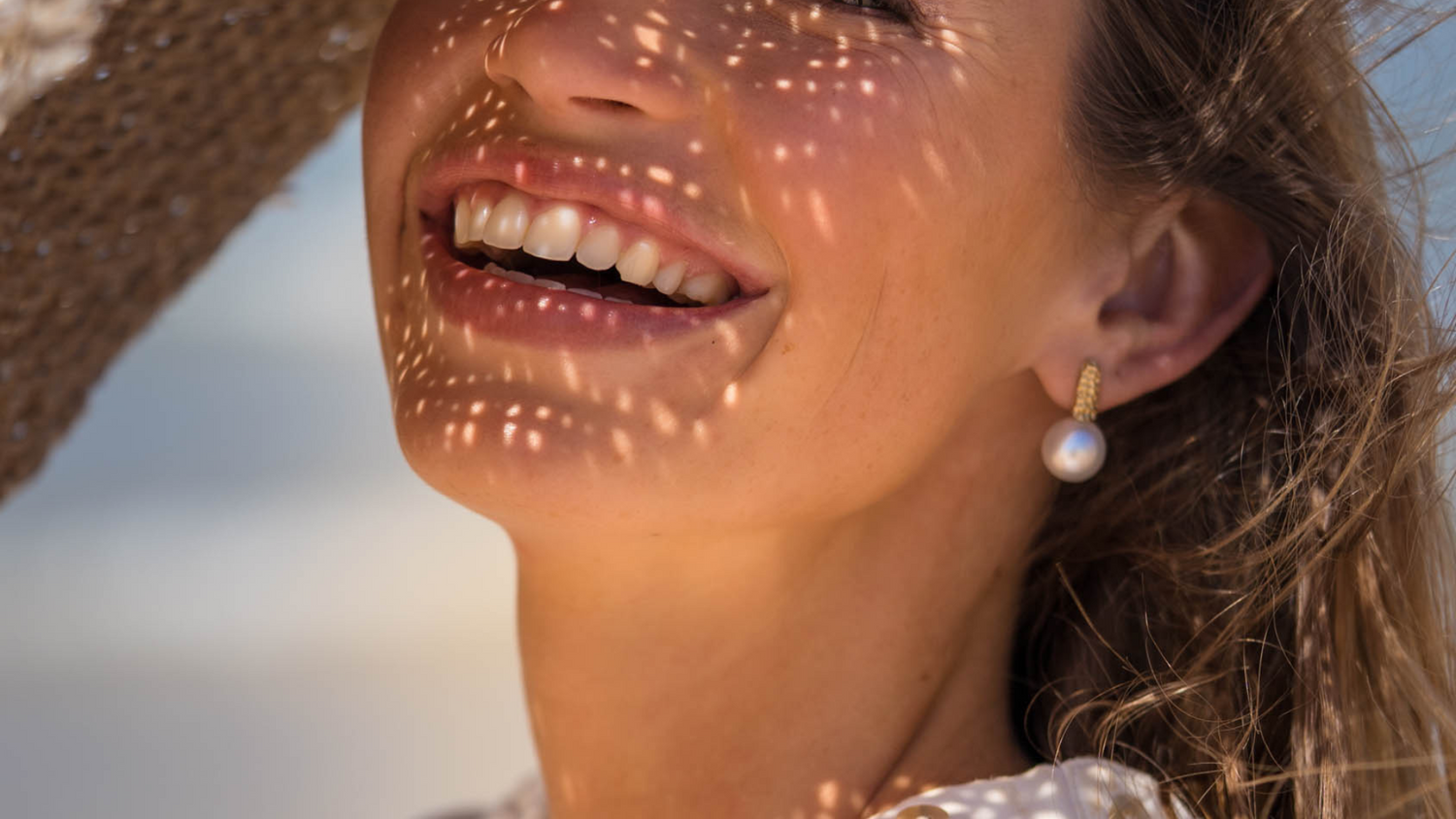 A woman smiles, wearing her stunning Impressions Studs that feature our Cygnet Bay grown Australian South Sea pearls.