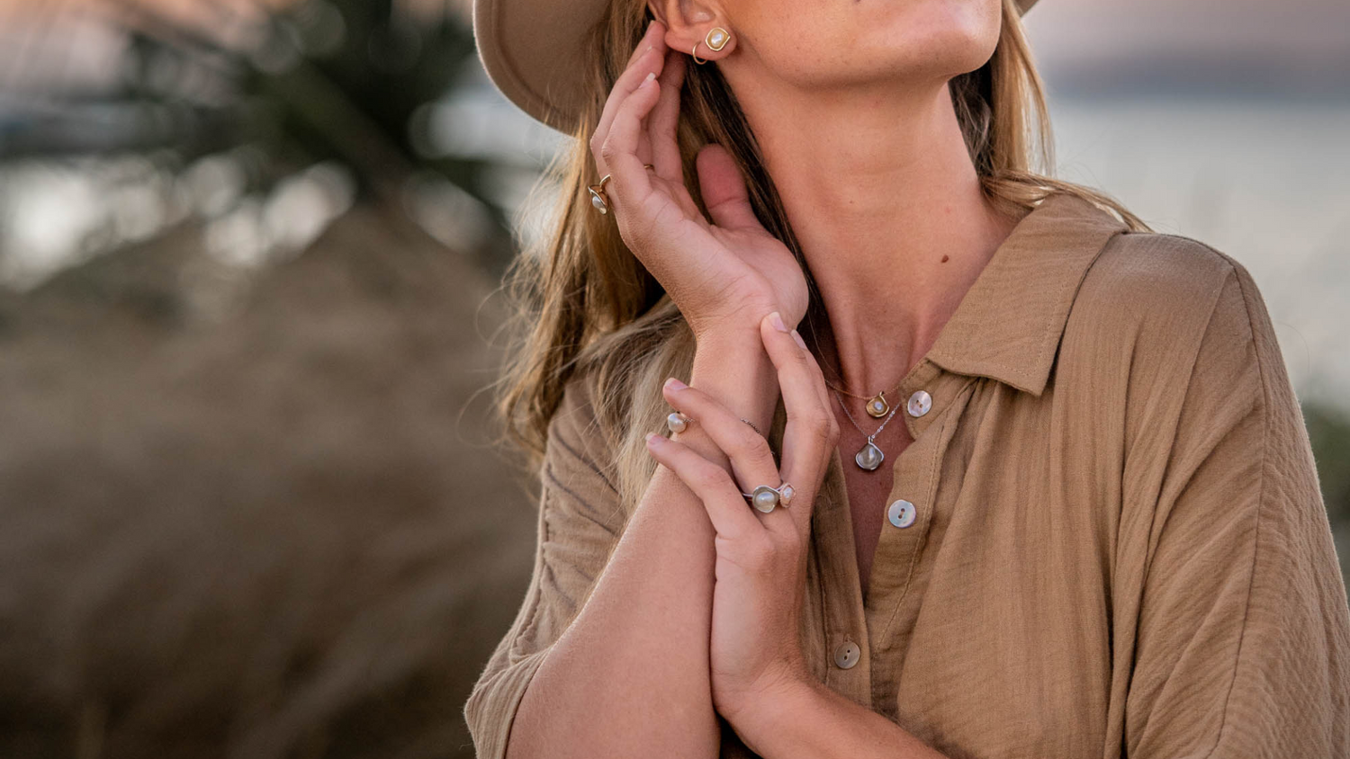 A woman watches the sunrise at Cygnet Bay Pearl Farm, while wearing her Kimberley Lily Keshi pearl jewellery collection set in various golds.