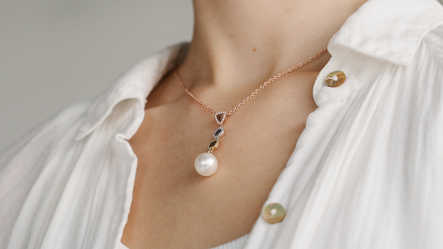 A woman wears her stunning limited edition pearl jewellery piece, which features our Australian grown saltwater pearls set alongside three types of metal and diamonds.