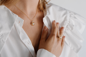 A model wears her stunning Mangrove Lily pearl jewellery set, featuring a pair of pearl studs and a pearl pendant designed in homage of the coastal marvel - the Mangrove Lily.