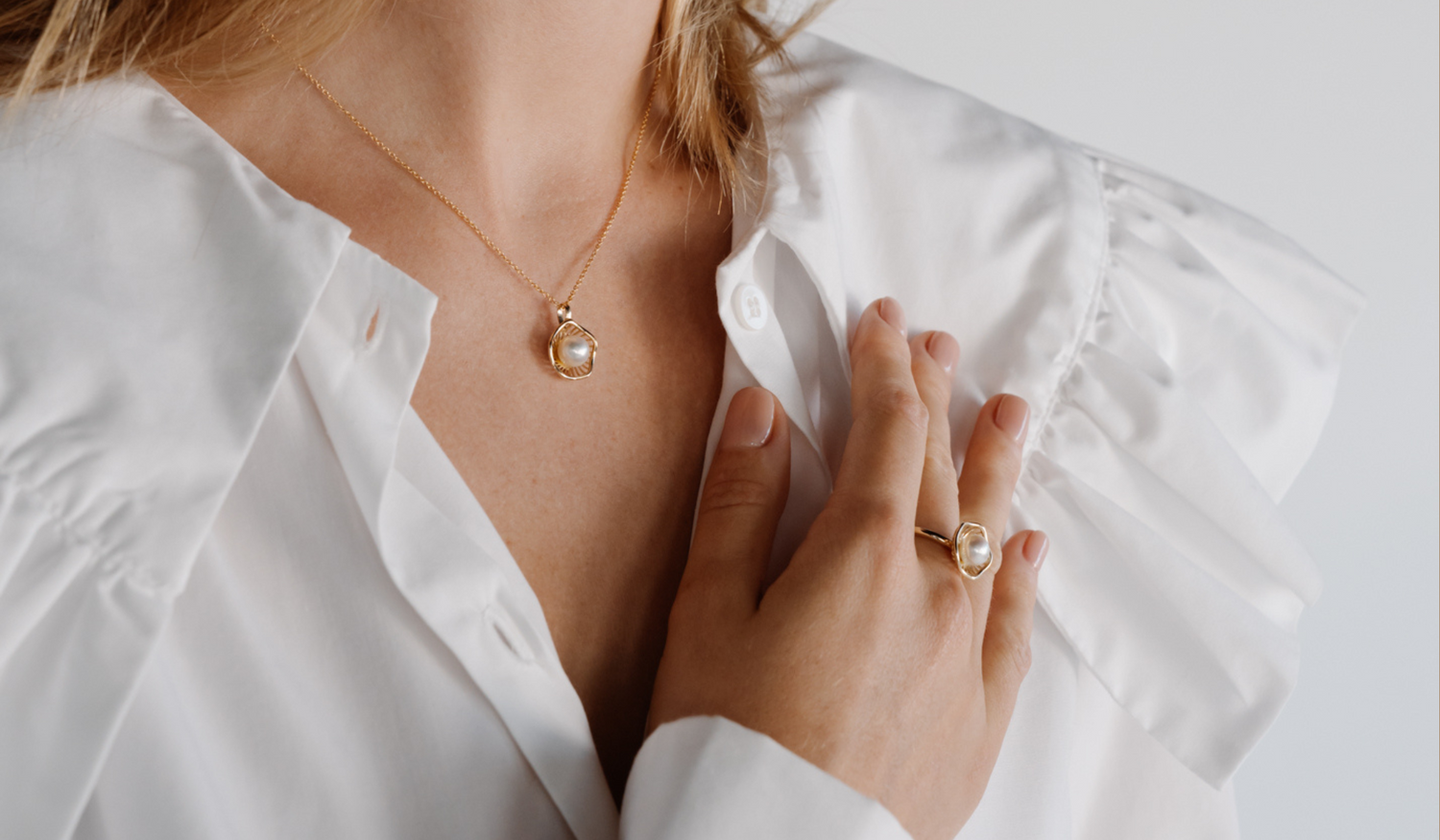 A model wears her stunning Mangrove Lily pearl jewellery set, featuring a pair of pearl studs and a pearl pendant designed in homage of the coastal marvel - the Mangrove Lily.