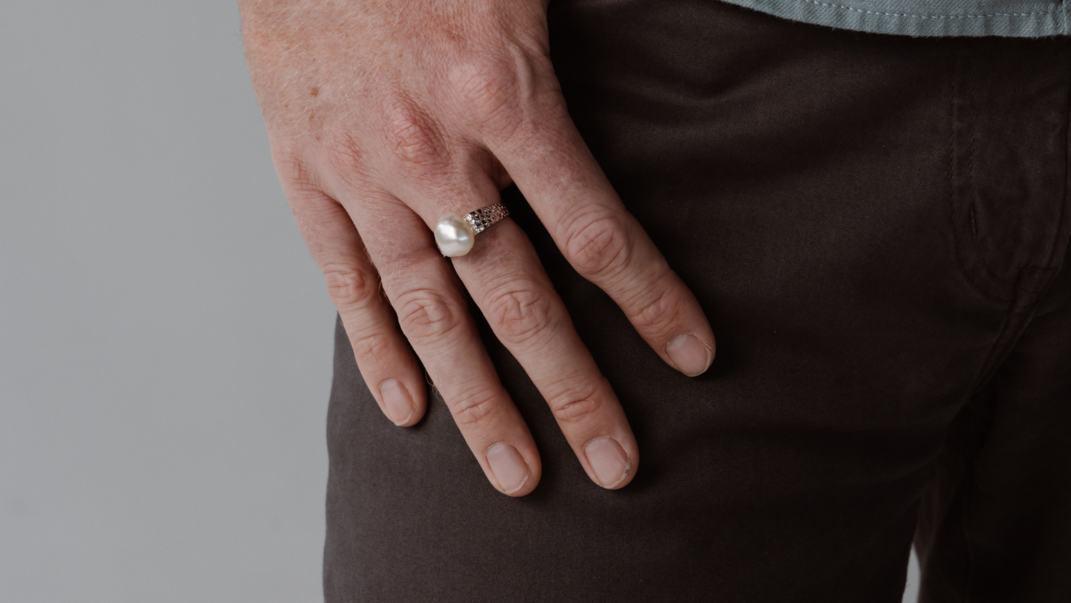 A man wears his statement pearl ring that features a thick gold band and Australian keshi pearl from our Cygnet Bay Pearl Farm. 