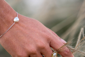 A woman wears her stunning chain bracelet that features an Australian Keshi pearl set on a delicate solid gold chain. 