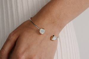 A woman wears her Mother of Pearl bangle, featuring faceted Mother of Pearl pieces grown at our Cygnet Bay pearl farm and set in 9ct yellow gold.