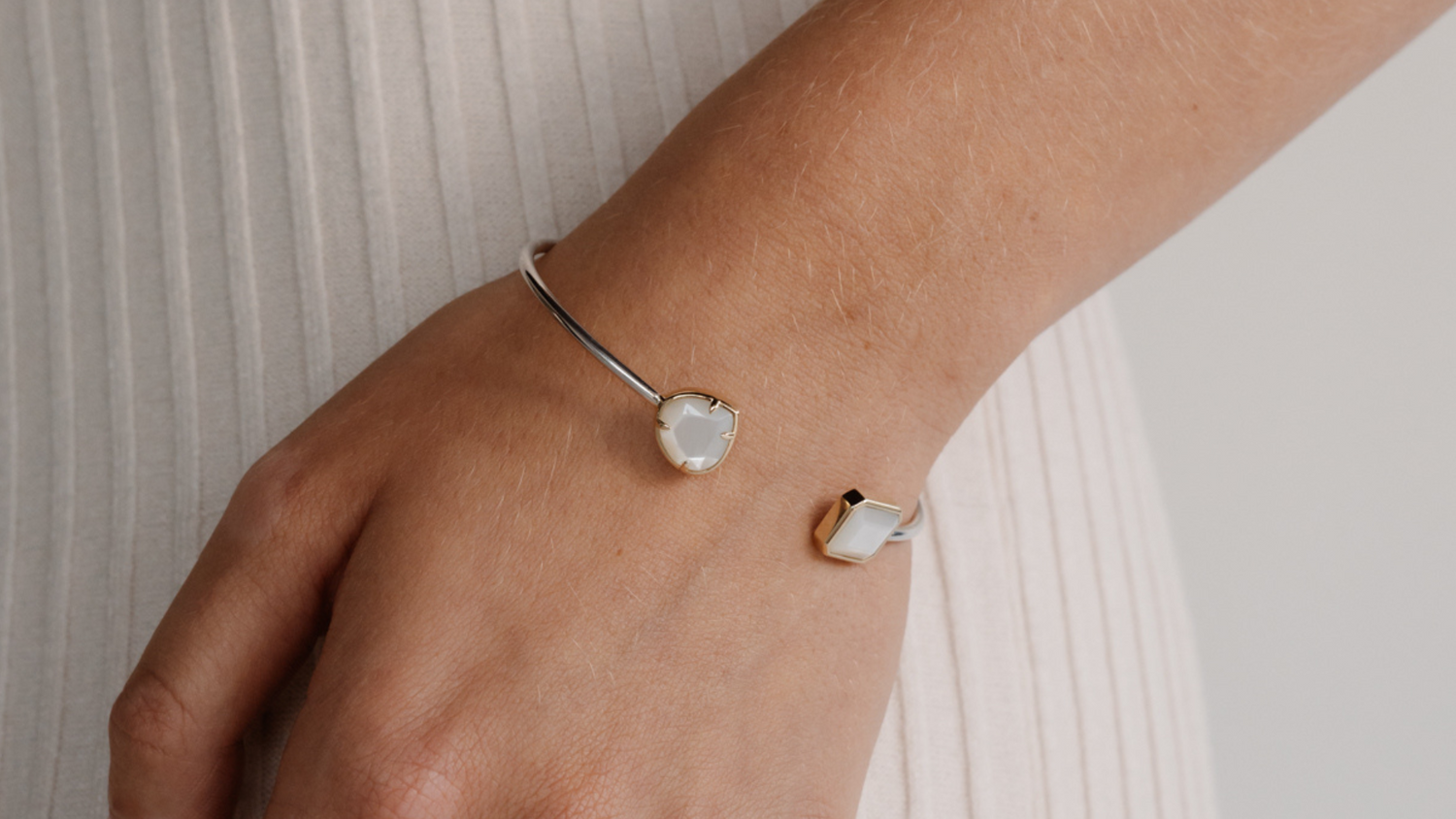 A woman wears her Mother of Pearl bangle, featuring faceted Mother of Pearl pieces grown at our Cygnet Bay pearl farm and set in 9ct yellow gold.