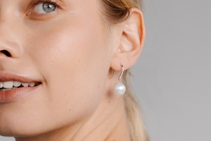 A woman wears her beautiful Nivea Pearl Hooks that feature a solitaire white diamond set alongside a white Australian South Sea pearl.