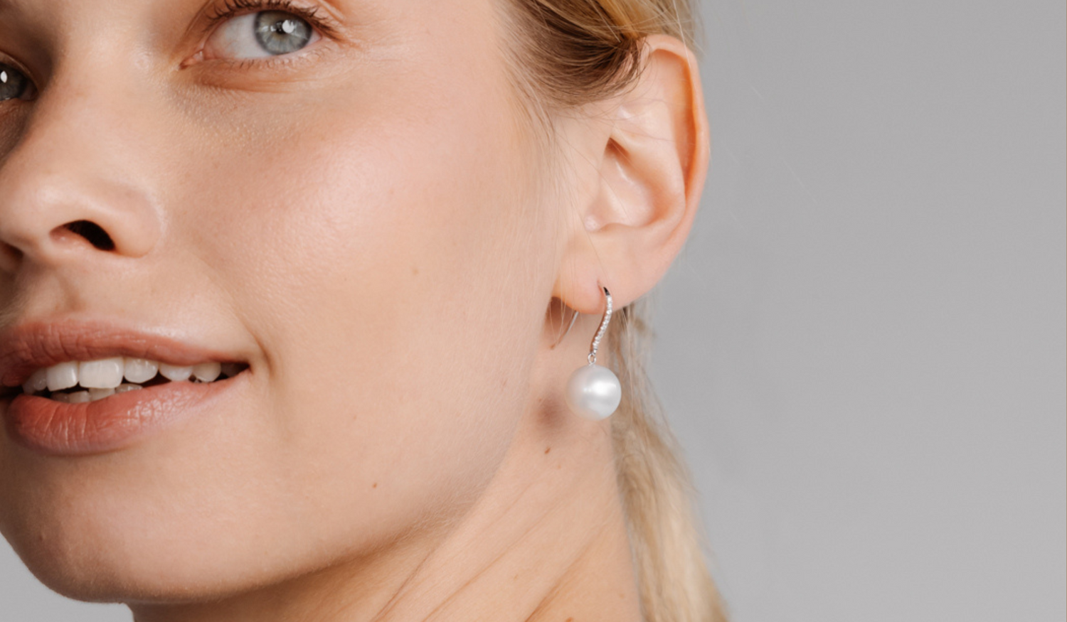 A woman wears her beautiful Nivea Pearl Hooks that feature a solitaire white diamond set alongside a white Australian South Sea pearl.