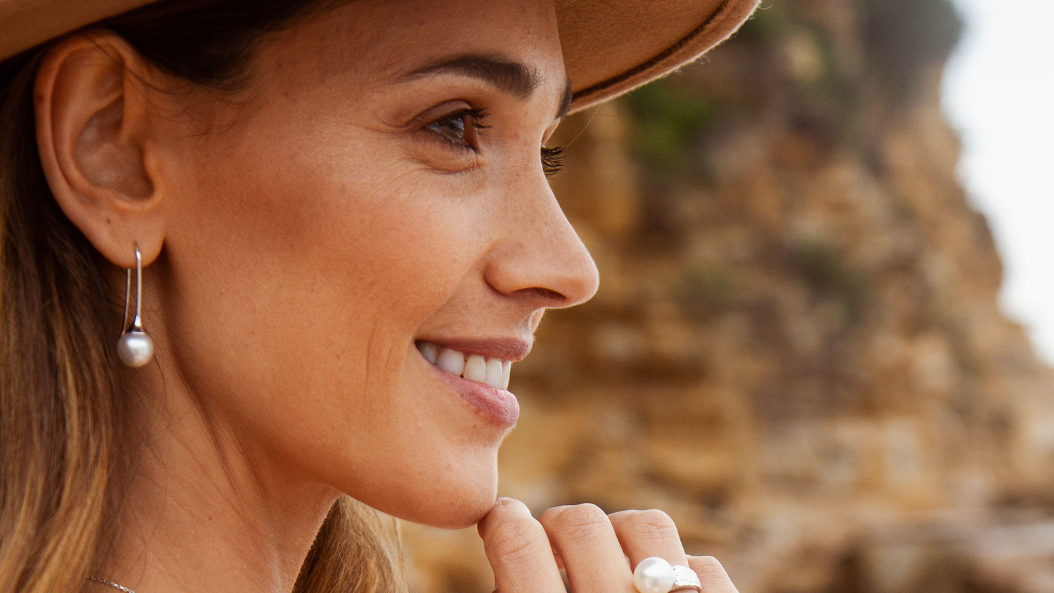 A woman wears her beautiful pearl hook earrings, that feature a striking, white Australian South Sea pearl.