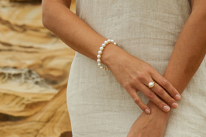 A woman wears her white pearl strand bracelet, each pearl perfectly matching the next.