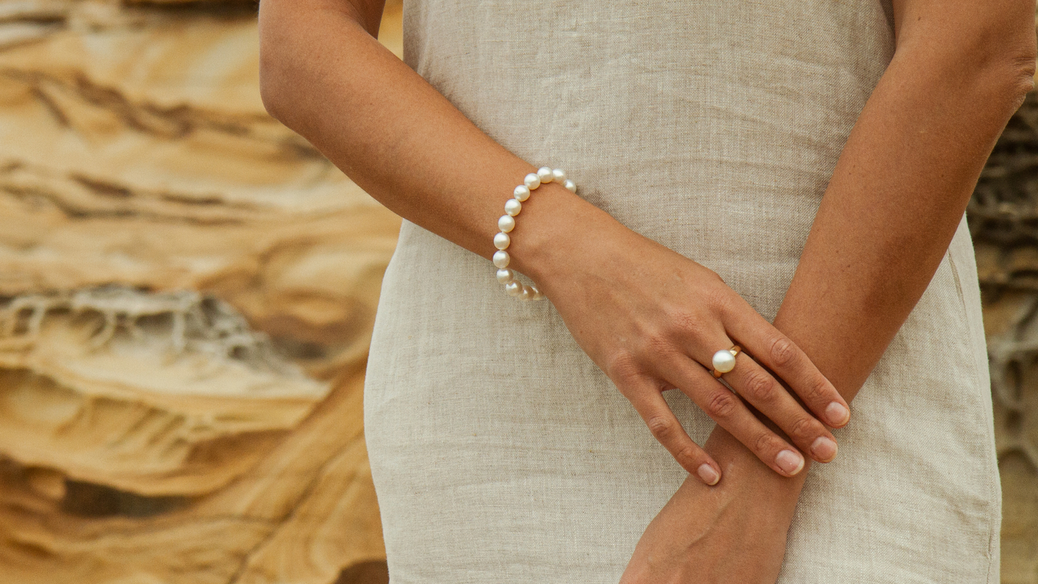 A woman wears her white pearl strand bracelet, each pearl perfectly matching the next.