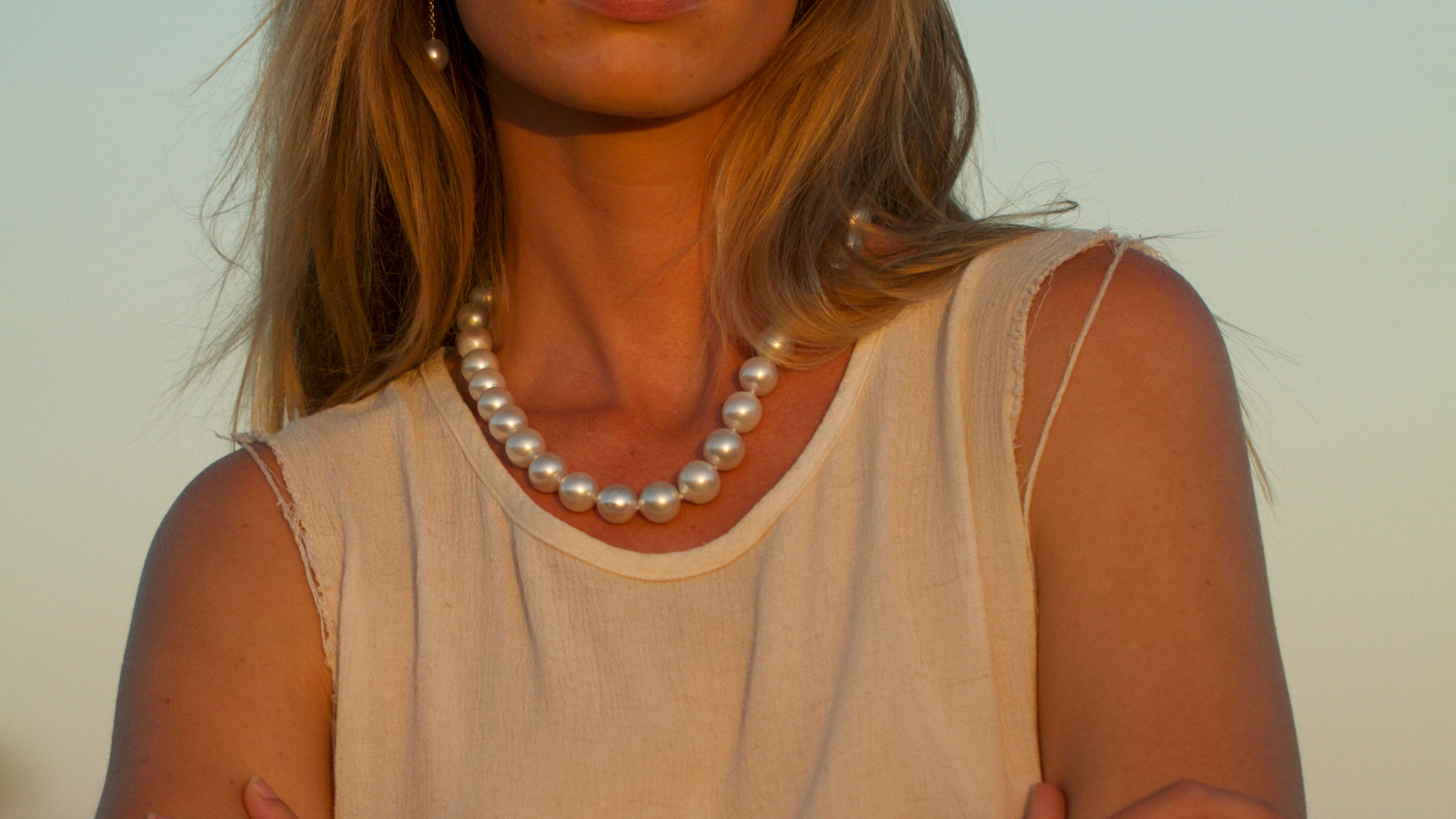 A woman gazes into the Kimberley sunset while wearing her Cygnet Bay grown Australian South Sea pearl strand necklace.