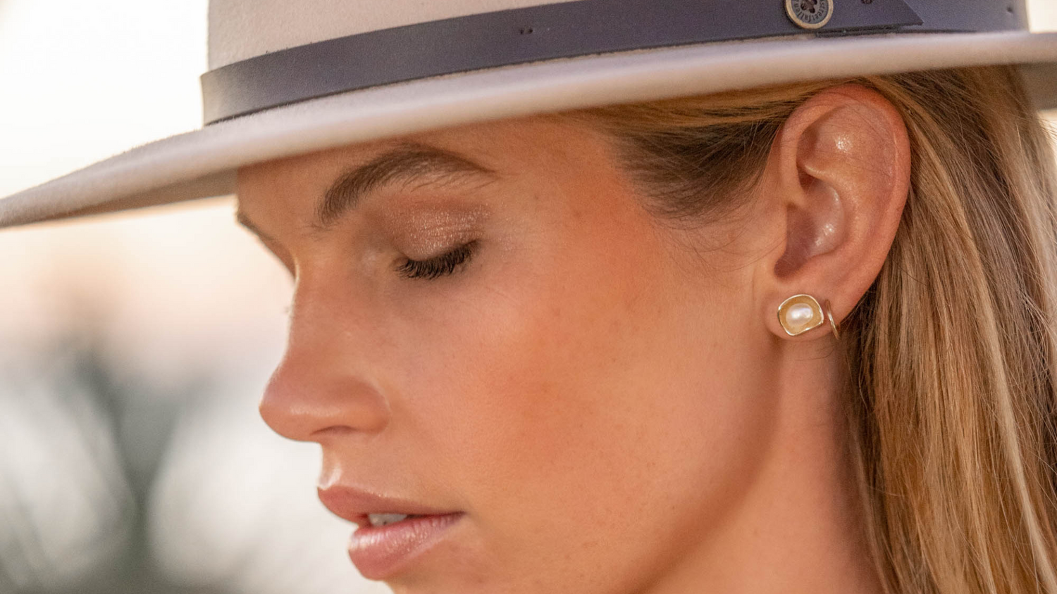 A woman wears her stunning Kimberley Lily studs that feature our Australian South Sea Keshi pearls set in gold.