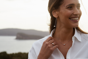 A woman wears her stunning Savanna pearl jewellery collection which features our Australian Akoya set in a pair of thread through earrings, and matching necklace.