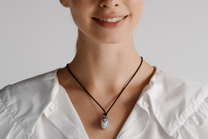 A woman wears her beautiful baroque pearl pendant set alongside beautiful black diamonds hung on a silk cord rope.