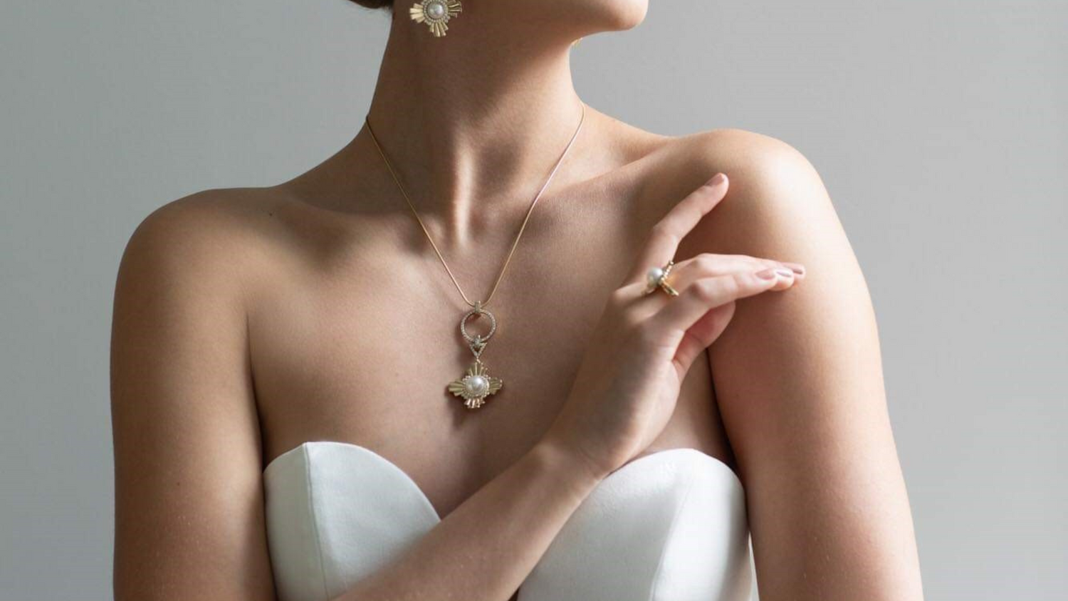 A bride wears her Star of the West set, which is a pair of pearl earrings, pearl pendant and pearl ring all designed with a nod to the art deco era.