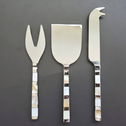 Set of three silver cheese tools with decorative handles on a dark background