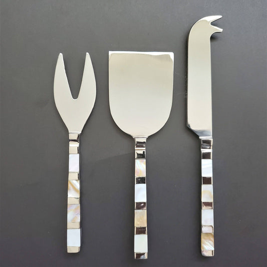 Set of three silver cheese tools with decorative handles on a dark background