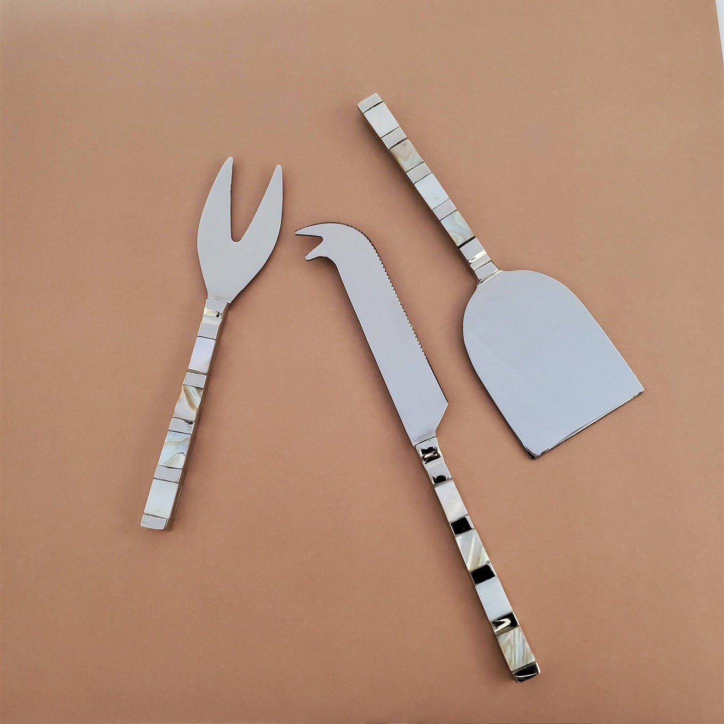 Set of three metal cheese tools on a brown background