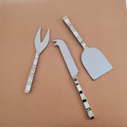 Set of three metal cheese tools on a brown background