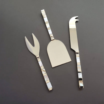 Set of three silver cheese knives on a dark gray background