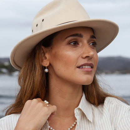 A woman wears her pair of classic Acacia Pearl Hooks featuring a pair of Cygnet Bay (WA) grown Australian South Sea pearls set in gold.