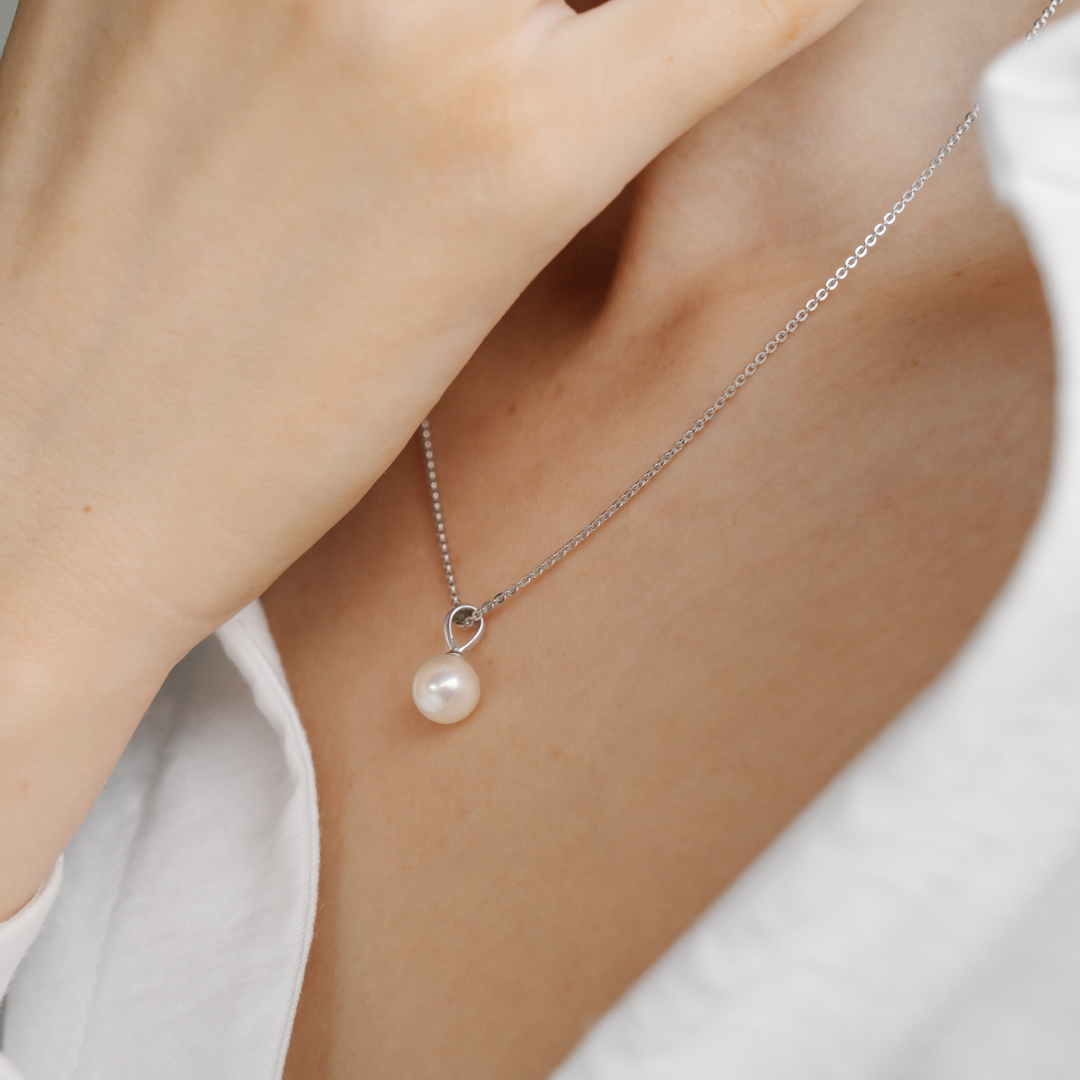 A person wears their stunning Broken Bay grown Akoya pearl pendant on a matching gold chain. 