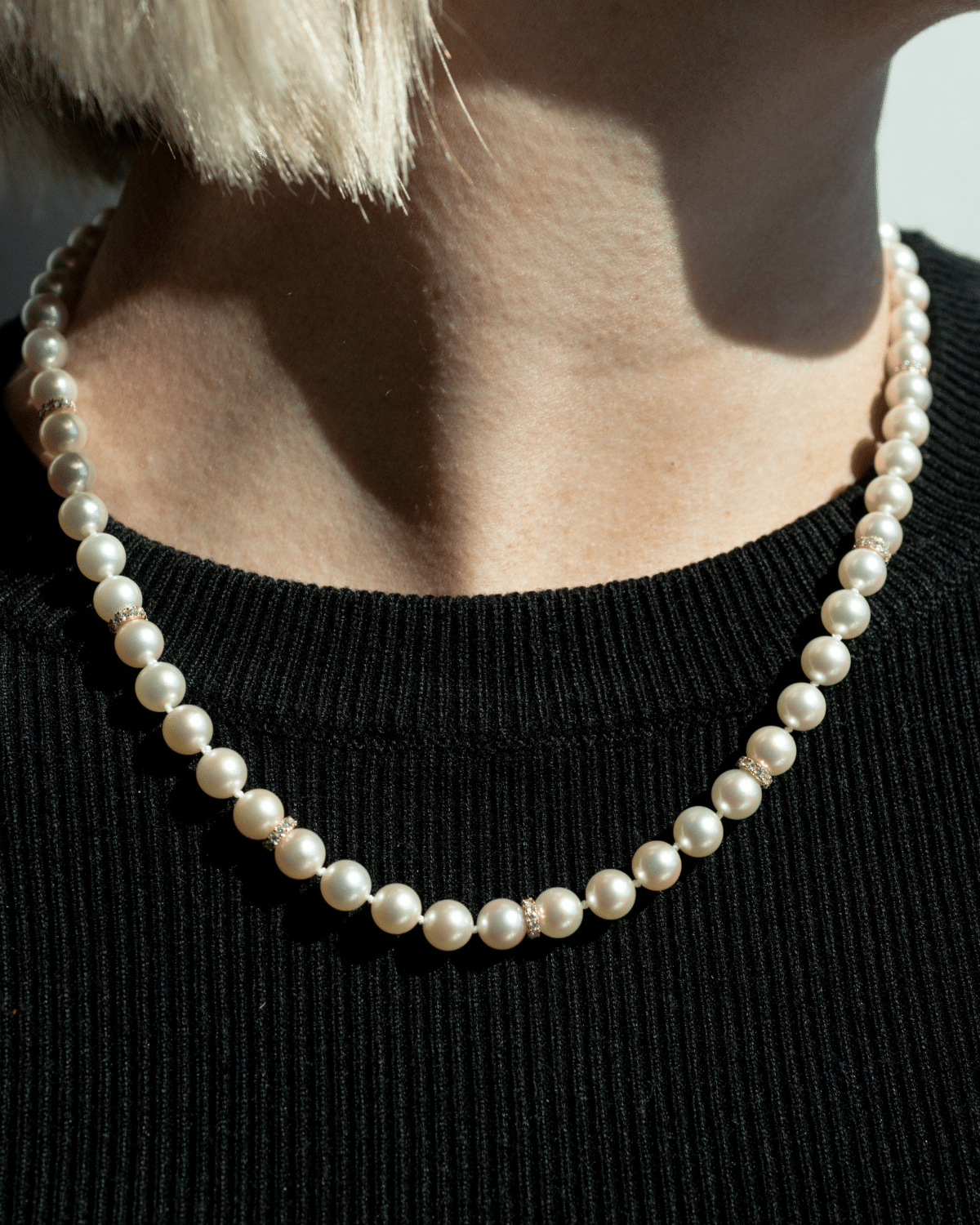 A woman wears her striking Pearl Strand Diamond Rondel Necklace features sixty (60) 6.5mm Round AAA grade Broken Bay (NSW) grown Australian Akoya pearls. This 46cm pearl strand is complimented by 77 White Diamonds, set with an 18ct Yellow Gold clasp.