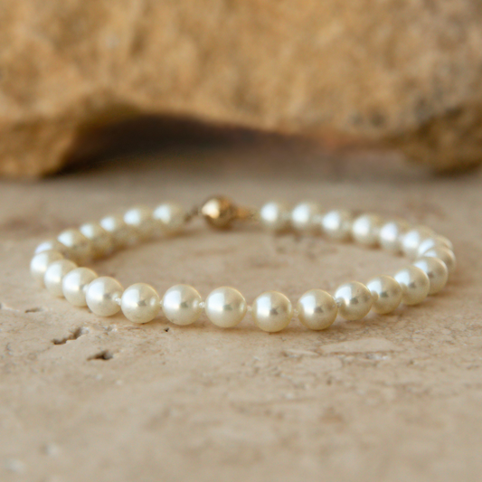 Pearl bracelet on a textured beige surface