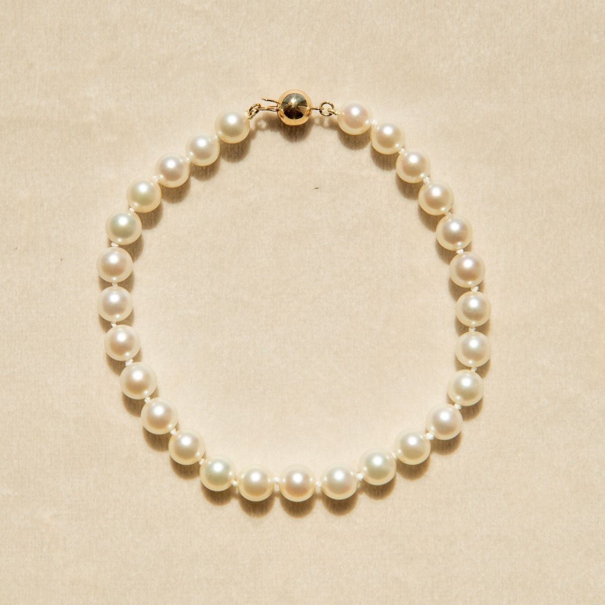 Pearl strand bracelet on a beige background