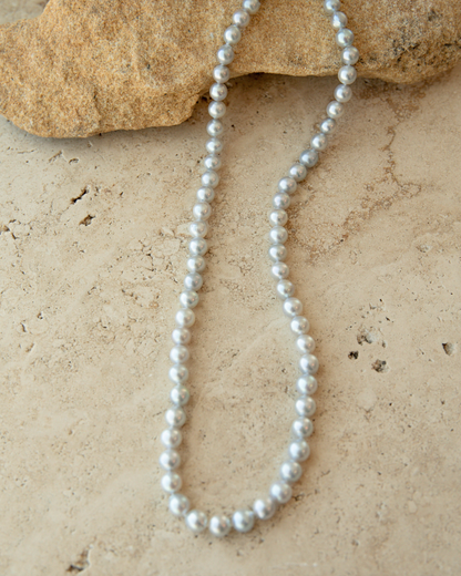 Akoya Pearl Strand necklace on a textured beige surface