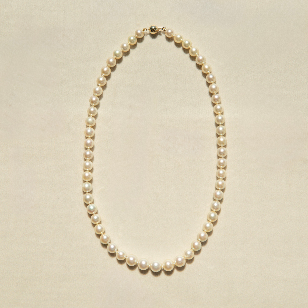 Pearl strand necklace on a beige background