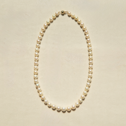Pearl strand necklace on a beige background